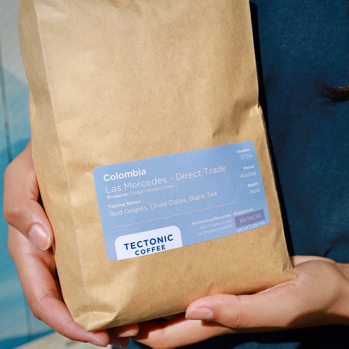 Hands holding a 1 kg bag of Tectonic Coffee Colombia Finca Las Mercedes.