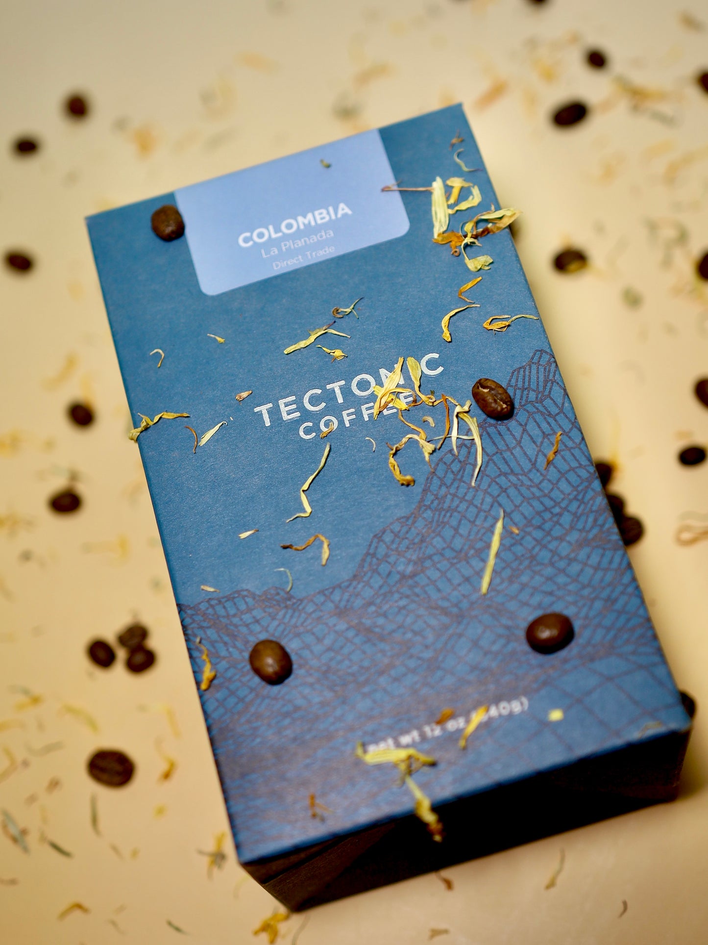 Tectonic Coffee packaging with coffee beans and gold leaf on a beige background