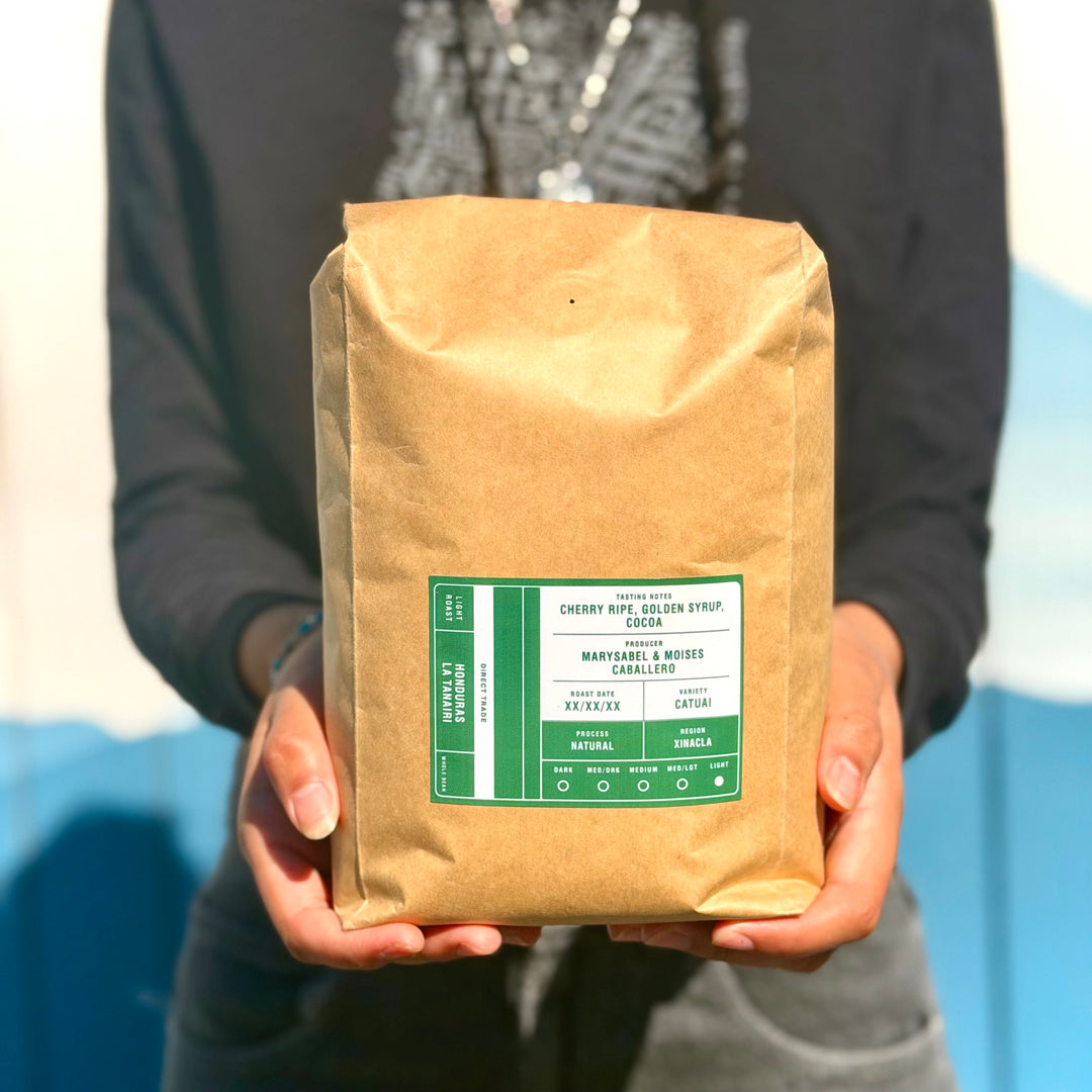 Person holding a 1 kg bag of Tectonic Honduras La Tanairi Natural whole-bean coffee.